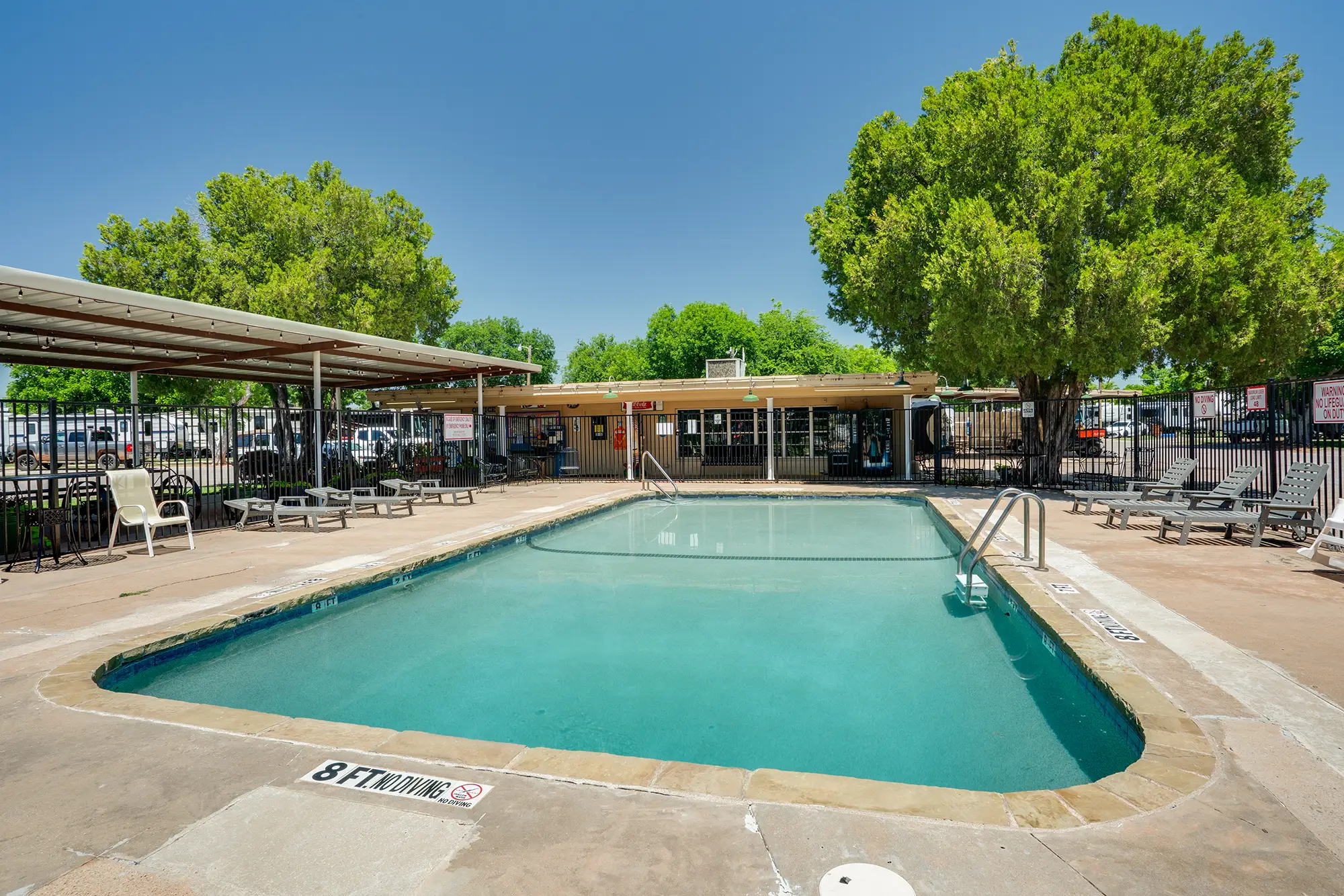 Refreshing swimming pool with shaded lounge area at Wichita Falls RV Park offering relaxing amenities for Texas travelers and families year-round.