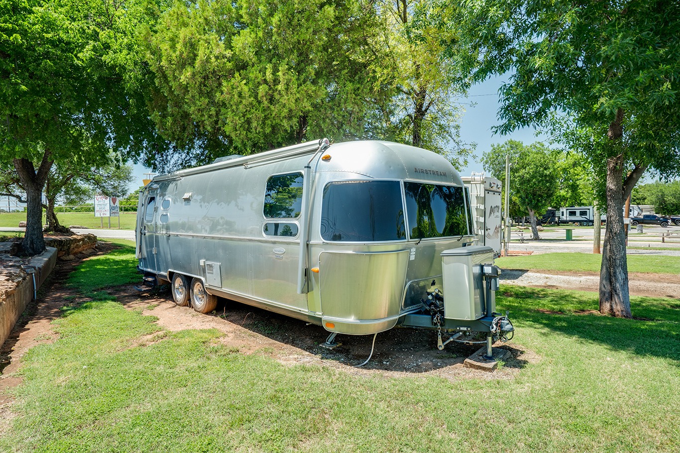 Airstream travel trailer at Wichita Falls RV Park with spacious shaded campsite, full hookups, peaceful setting, and convenient access to local attractions.