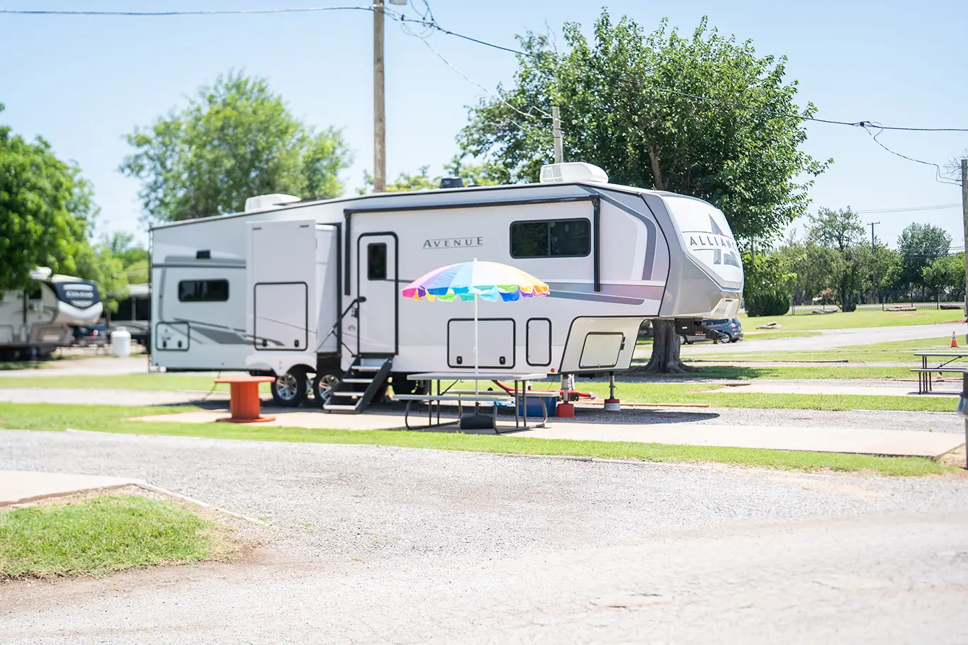 Fifth wheel RV parked at Wichita Falls RV Park with full hookups, concrete pad, picnic table, shaded campsite, family-friendly atmosphere year-round.
